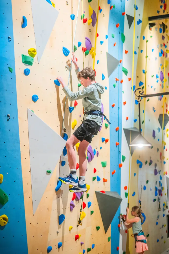 Enfants grimpant sur un mur d’escalade coloré en salle