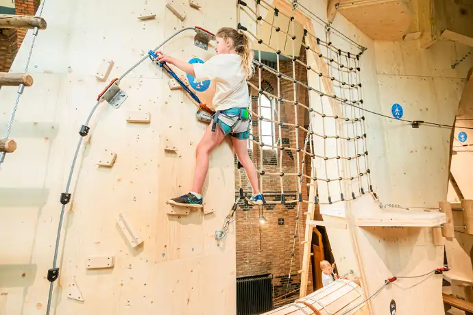 Enfant grimpant sur un mur d’escalade intérieur en bois